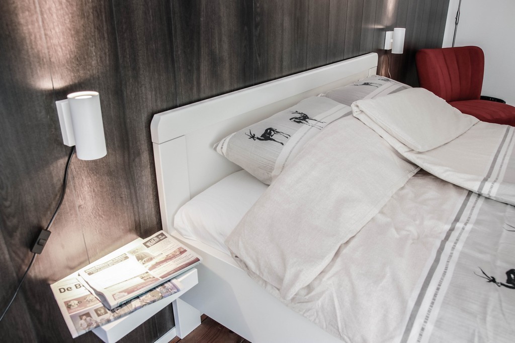 Opgemaakt bed met kranten op nachtkastje