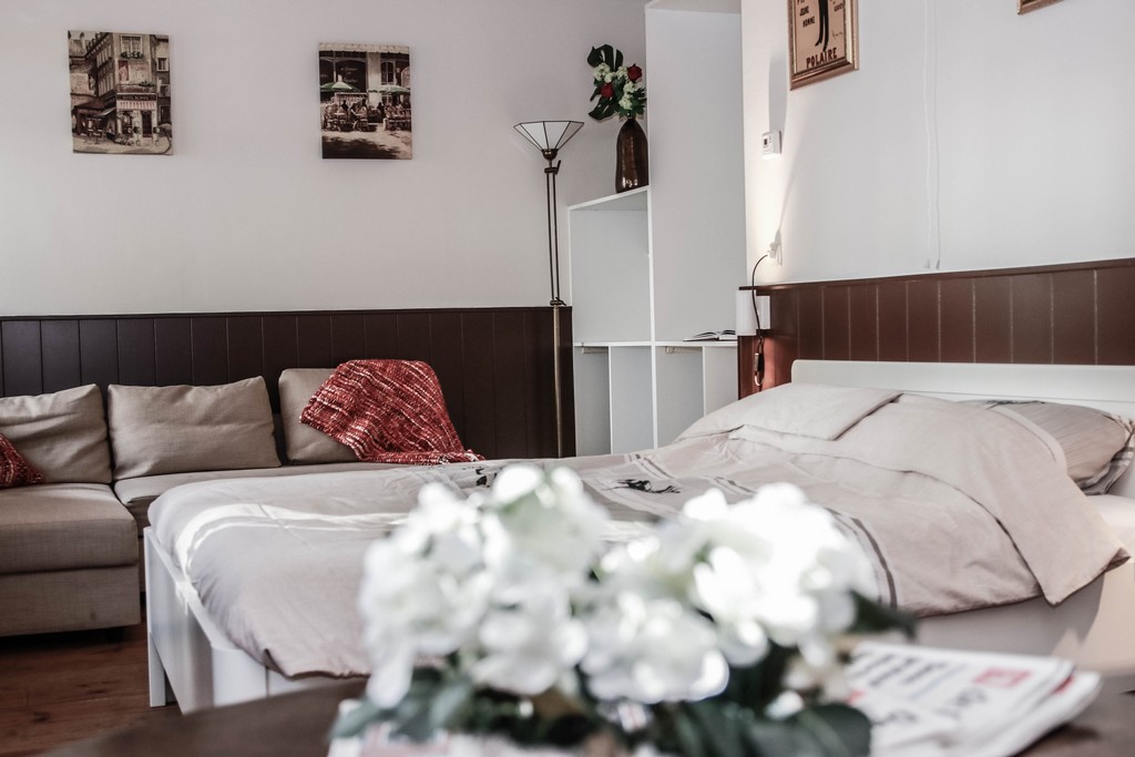 Kamer met onscherpe bloemen lambrizering, stoel op voorgrond, bed, bank en kast